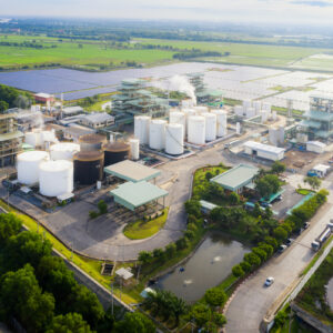 Aerial view photo of industrial zone showing oil refinery with storage tank with solar farm power station for renewable energy supply.