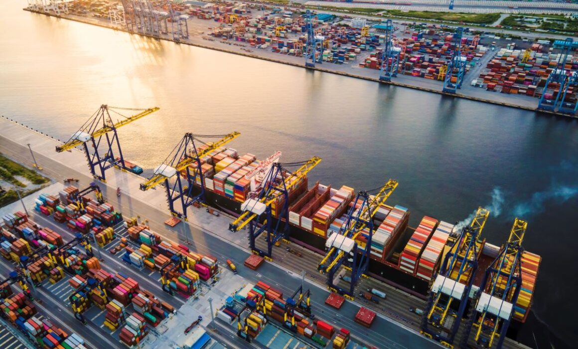 Port of entry showing shipping containers being stacked by cranes.