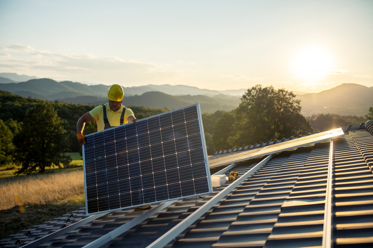 Technician fitting solar panels to a house roof.