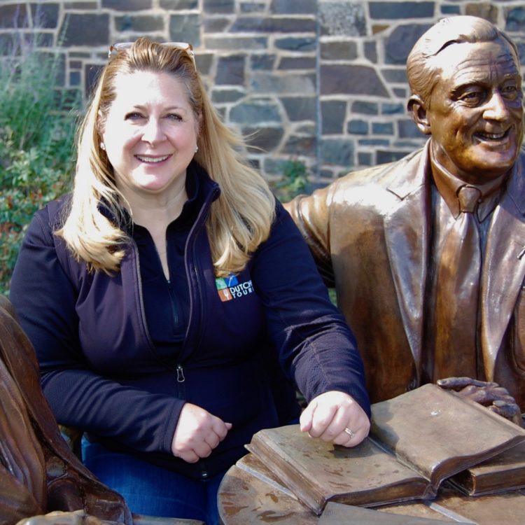 Melaine Rottkamp, a white women, sitting with the FDR statue at the FDR Presidential Library