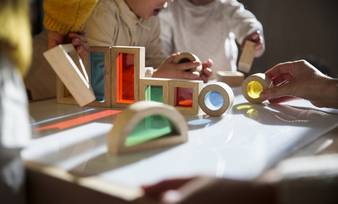 Little kids playing with colorful wooden building blocks on the table